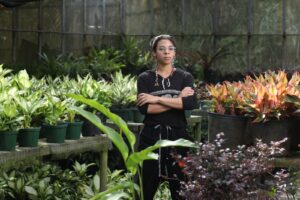 Una estudiante dentro del invernadero rodeada de plantes.