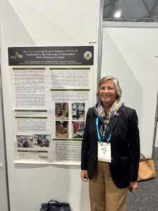 doctora Wanda Maldonado posando al lado del afiche