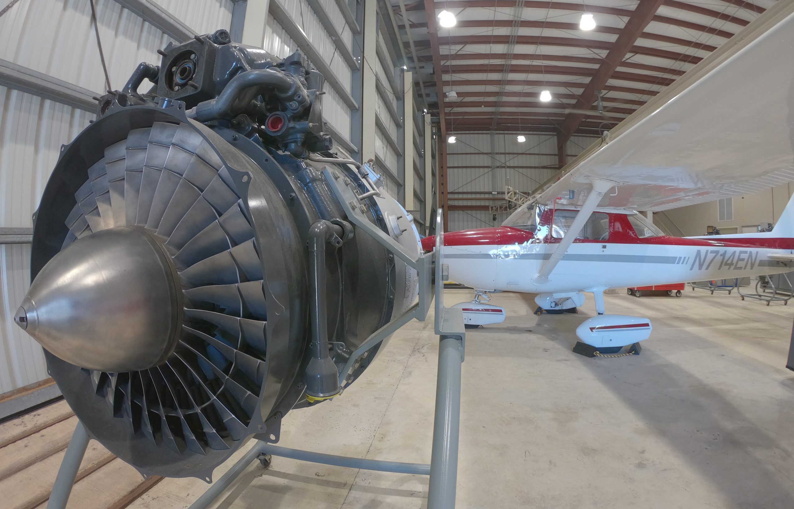 Foto de una turbina de avión montada en un armazón. La turbina está ubicada dentro de un hangar.