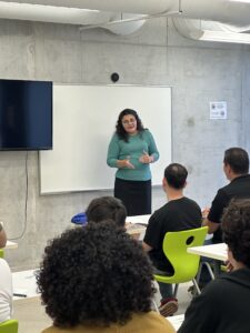 Acercamiento de instructora frente a los estudiantes en un salón de clases.