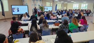 vista alejada del salon de conferencia lleno de espectadores.