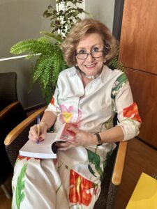 Doctora Carmen Cazurro sentada firmando un libro en su falda.