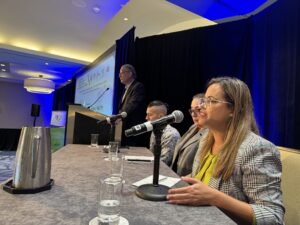 Invitado en seminario sentado en una mesa hablando por micrófono