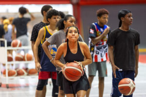 Joven se prepara a lanzar la bola de baloncesto al canasto.