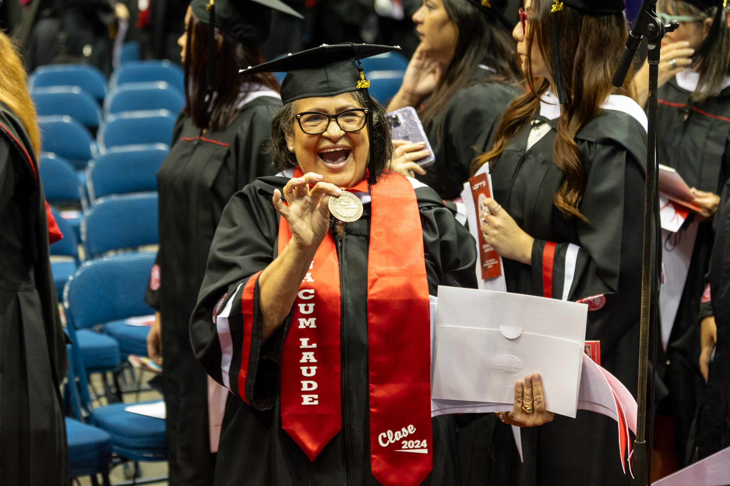 Grad-42 Estudiante graduada mostrando orgullosamente su medalla de alto honor.