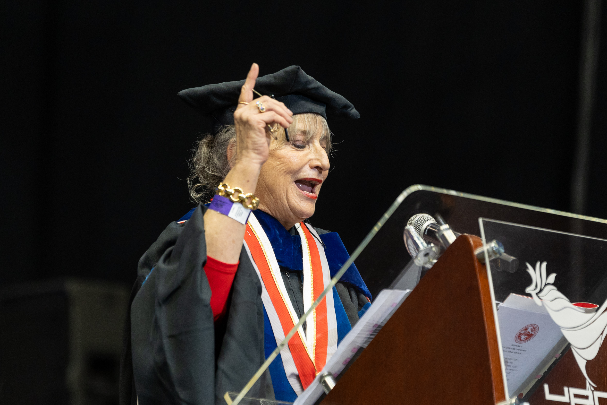 Grad-9 Profesora frente al podio declarando.