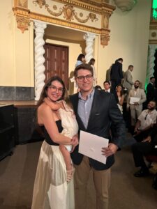 Padre graduado con su certificado en mano acompañado de su esposa e hija.