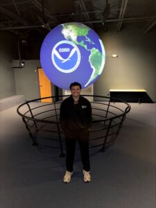 Luis Miguel frente a holograma de un globo terraqueo con el logo de NOAA