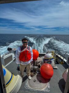 Luis Miguel de pie mirando a la camara en un bote en movimiento