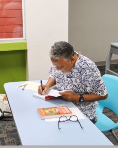 Doctor Manuel Valdés Pizzini, profesor emérito de la Universidad de Puerto Rico, escribiendo dedicatoria en la conraportada del libro "Memorias de la Costa".