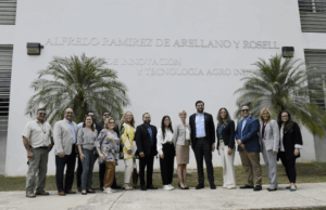 Grupo de personas posando frente al edicio Alfredo Ramiez de Arellano y Rosell. En el centro del grupo se encuentra el secretario del Departamento de Desarrollo Económico y Comercio, Sebastián Negrón Reichard.