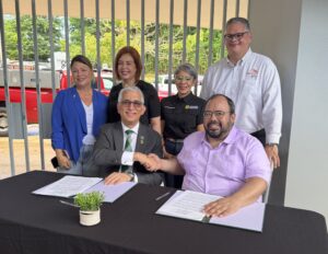 Agustín Rullán Toro, rector del RUM y el licenciado Eliezer Ramos Parés, secretario de Educación estrechando las manos luego de haber firmado los documentos. 