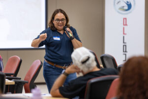 Maritza Barreto Orta con microfono en mano dando taller sobre erosión de costas.