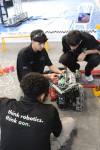 Tres estudiantes revisando un robot en el piso.