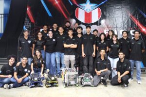 Foto del equipo AON Robotics del Recinto Universitario de Mayagüez. En el piso, 4 robots que el equipo construyó.