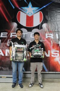 Dos estudiantes con sus respectivos robots en sus manos.