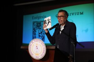 Profesor Carlos R. Gómez Beras en el podio, mostrando la revista Cuadrivium