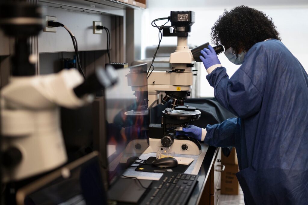 Investigador en laboratorio observando por un microscopio.