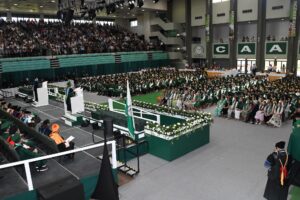 Vista aerea del coliseo: La tarima, estudiantes y publico en las gradas.