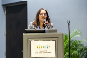 Doctora Maritza Barreto en un podio dirigiéndose al público.