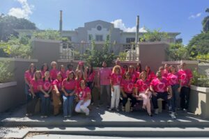 Foto grupal de los empleados con sus camisas rosadas.